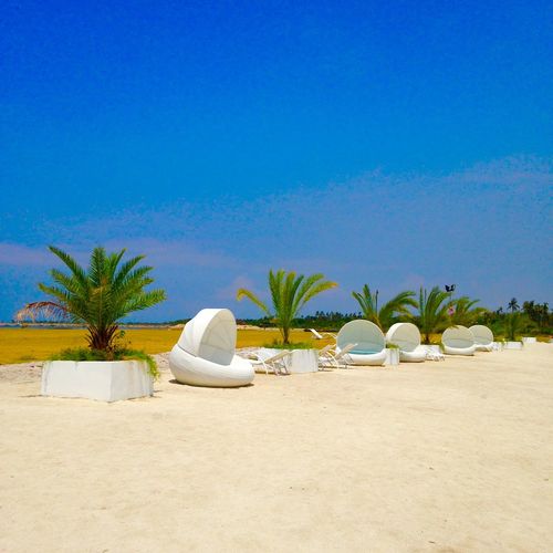 Lounge chairs on beach against clear blue sky
