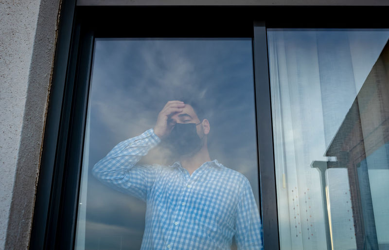Reflection of man looking through window
