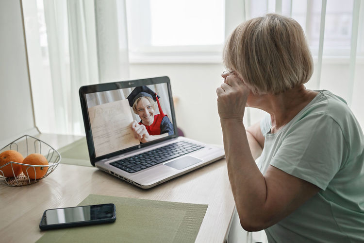 Woman video conferencing over laptop on table at home