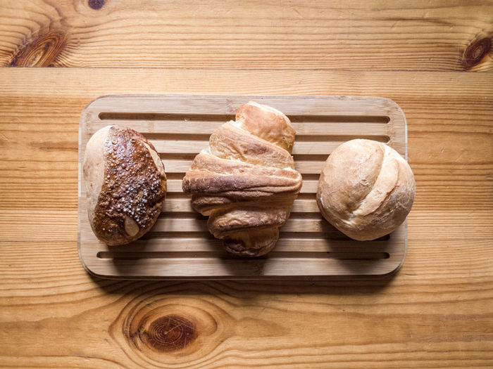 High angle view of three different breads on wooden plate
