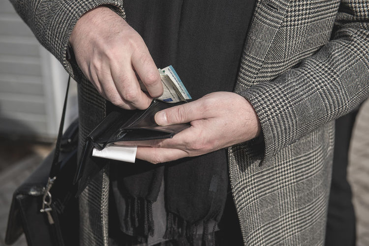 Midsection of man keeping paper currency in wallet