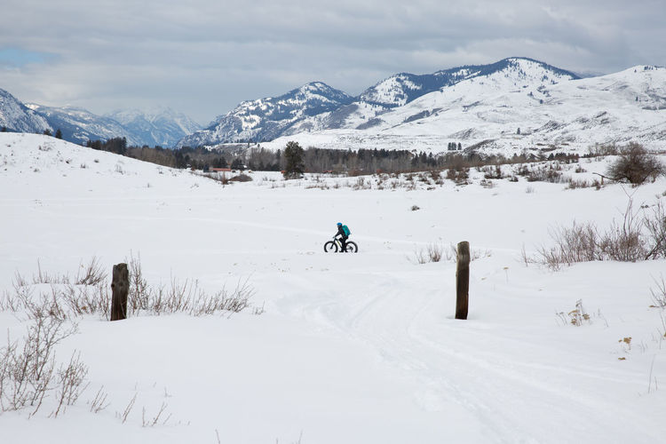 Woman cycling on snow covered field