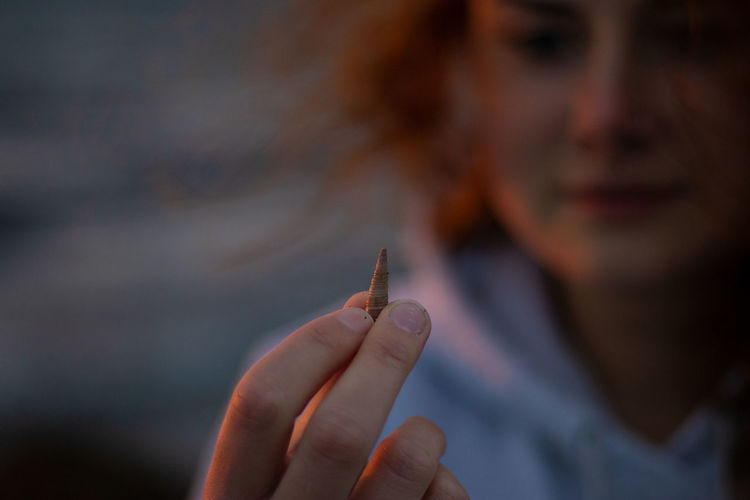Tiny shell held in hand on a beach at sunset