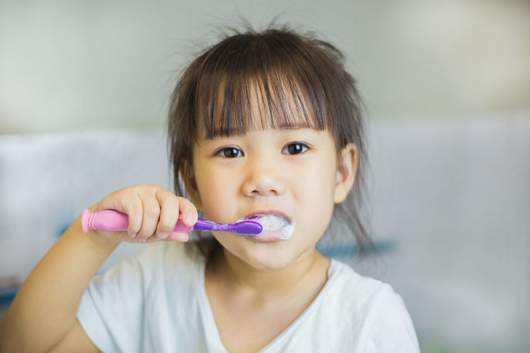 Portrait of cute girl brushing teeth at home