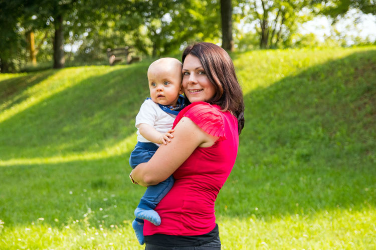 Happy mother with baby girl on grassy field