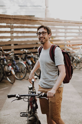 Portrait of smiling young man with bicycle in city