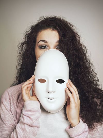 Portrait of beautiful woman with mask against white background