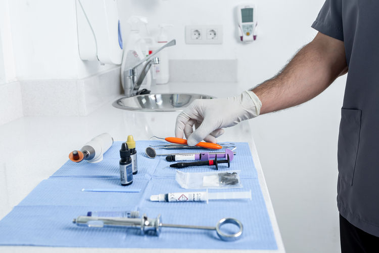 Croped photo of a person taking a instrument from a table with sterile tools for a dental clinic