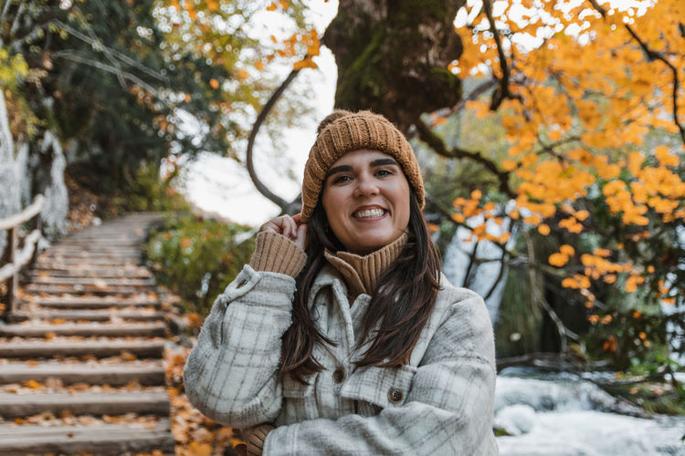 Portrait of beautiful woman standing on path in park in autumn