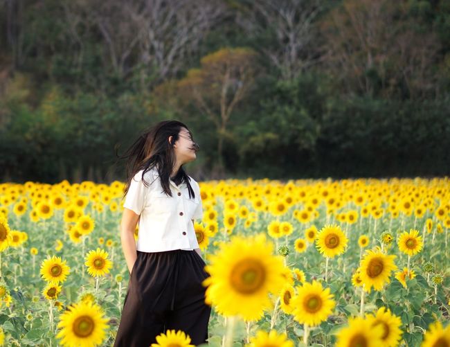 Portrait of young woman standing against plants