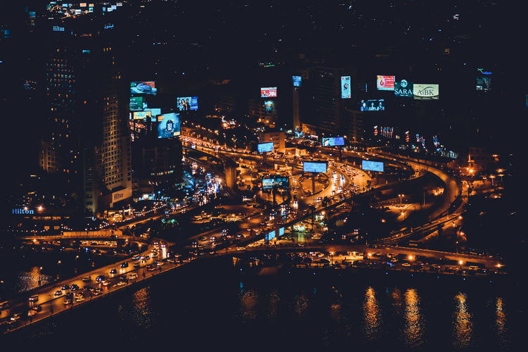 High angle view of river by illuminated city at night