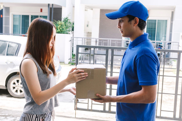 Woman receiving package from salesman while standing at doorway
