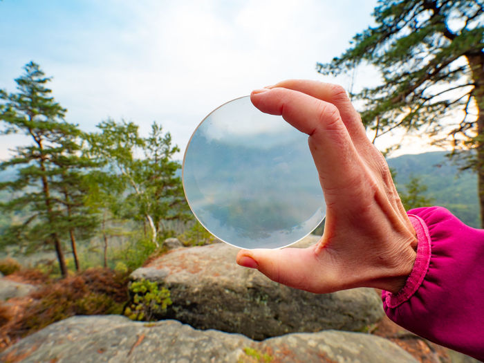 Blurry mountains captured in glass ball reflection hold in fingers. saxon switzerland, deutschland