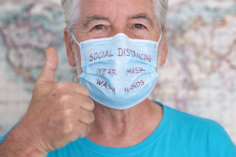 Close-up portrait of man wearing mask with text