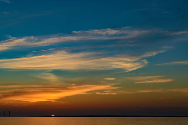 Scenic view of sea against dramatic sky during sunset