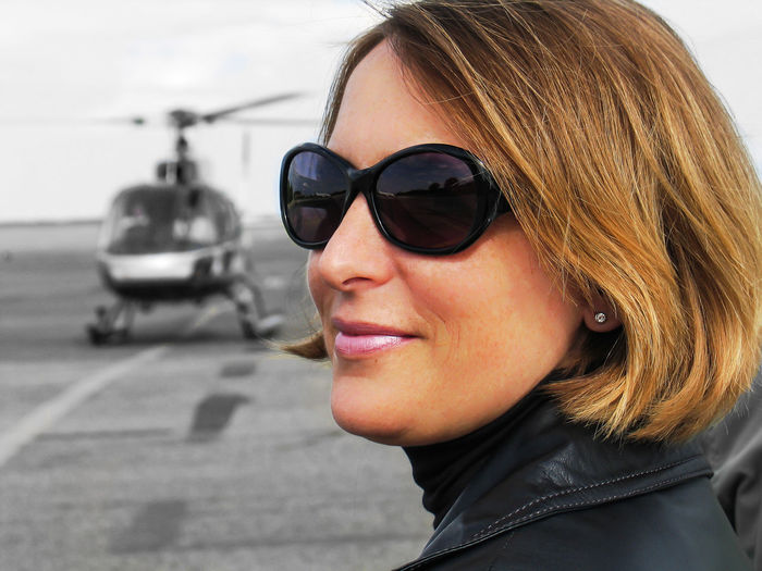 Close-up of smiling woman looking away against helicopter