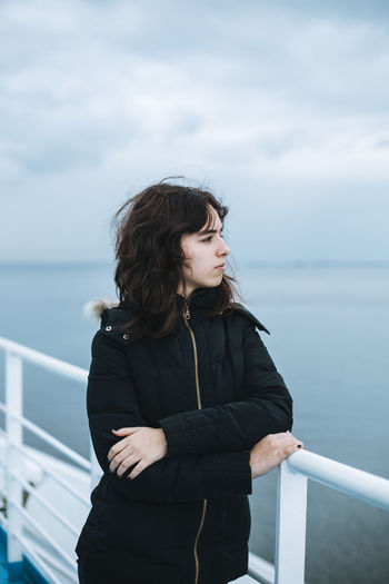 Pensive young girl looking to sea from boat. teenager girl at ferryboat. cold grey sea