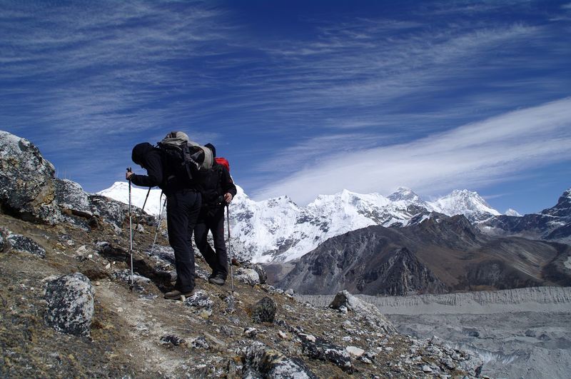 Rear view of people on snowcapped mountain against sky