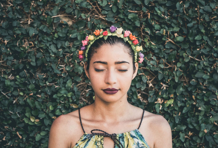 Close-up of woman wearing flowers against plants