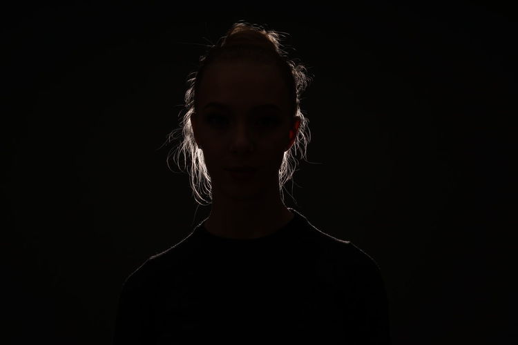 Portrait of a young woman over black background