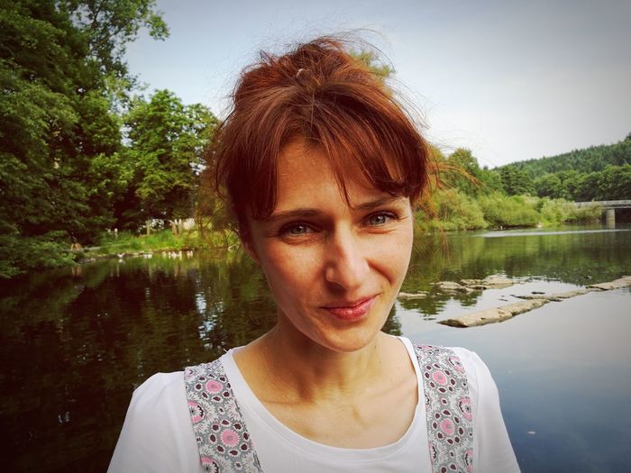 Portrait of woman by lake against trees