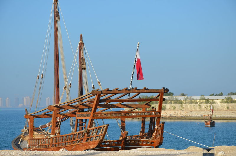 Sailboat moored on sea against clear blue sky