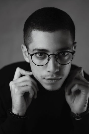 Portrait of young man wearing eyeglasses against curtain 