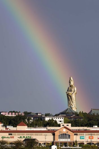 Statue of rainbow over building against sky