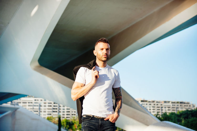 Portrait of young man standing against built structure