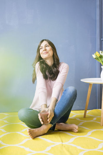 Portrait of a smiling young woman sitting on floor