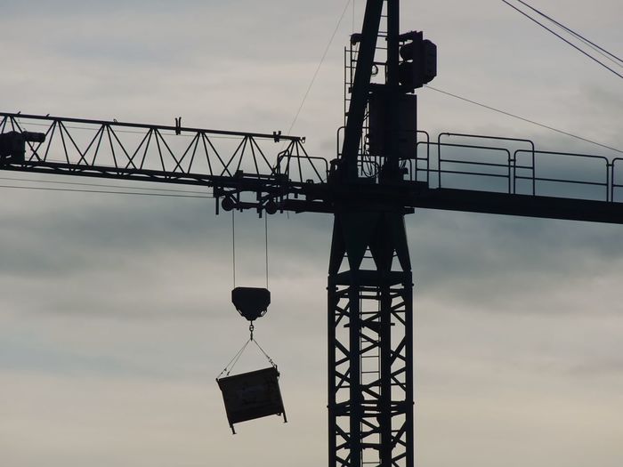 Low angle view of silhouette crane against sky