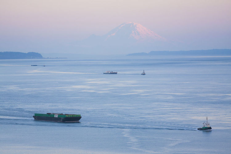 Tugboats pull barges in puget sound below mount rainier, washington