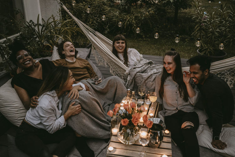 Cheerful friends enjoying at garden party in yard during sunset