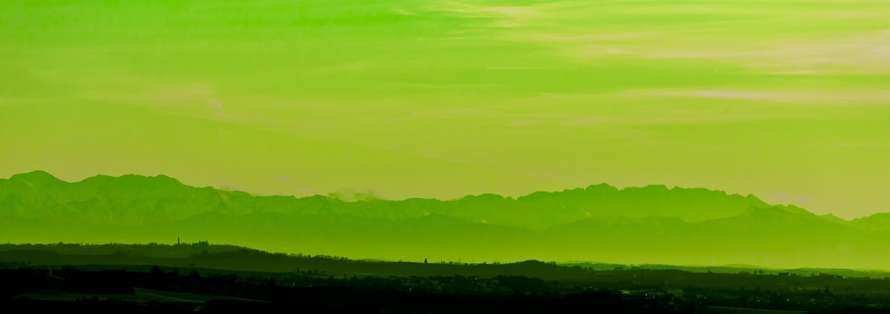 Scenic view of green landscape against sky during sunset