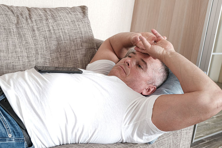 Midsection of man lying on bed at home