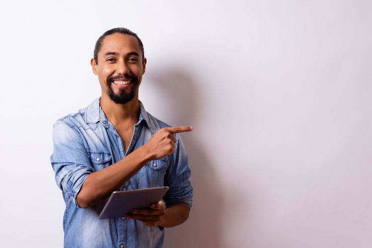 Portrait of young man using smart phone against white background