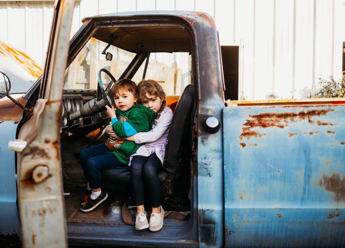 Young brother and sister sitting and hugging in vintage truck