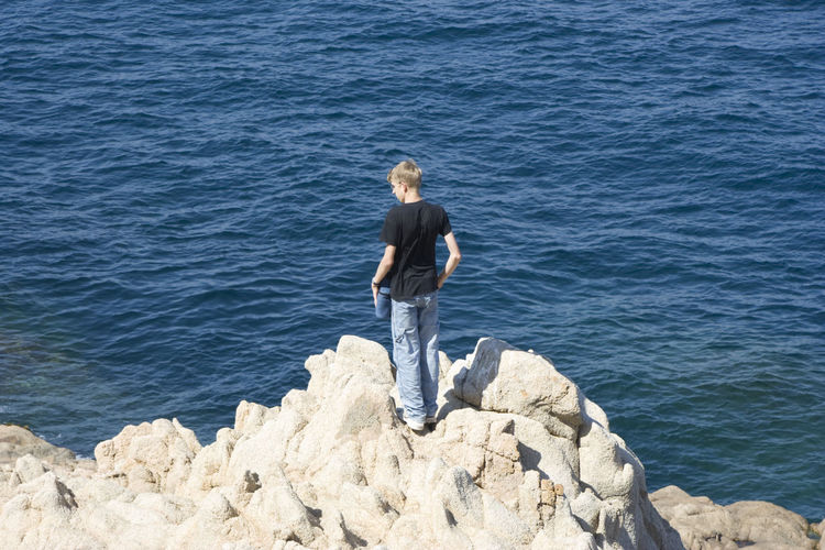 Rear view of teenager boy standing on seashore