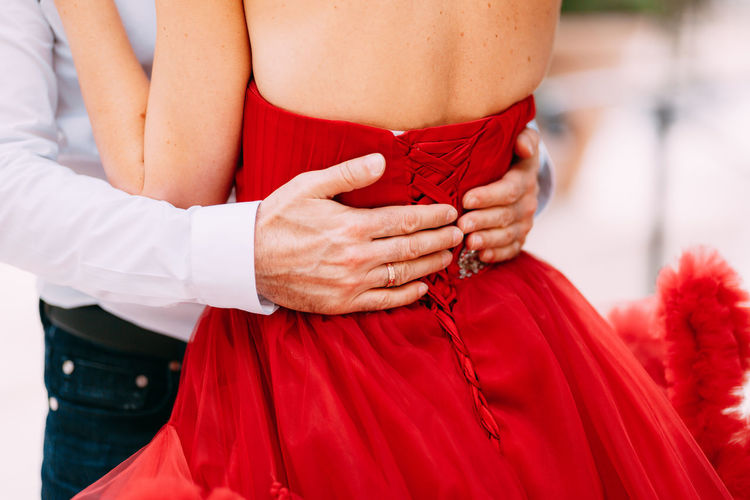 Midsection of couple holding red hands