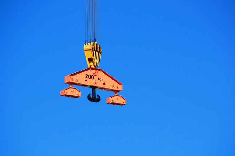 Low angle view of crane pulley against clear blue sky