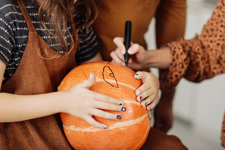 Midsection of woman drawing on pumpkin