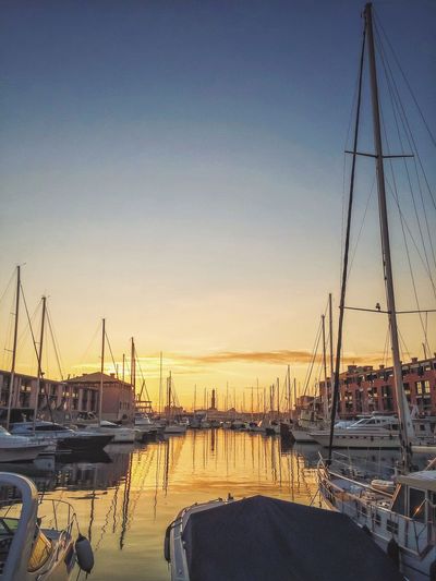 Sailboats in sea at sunset
