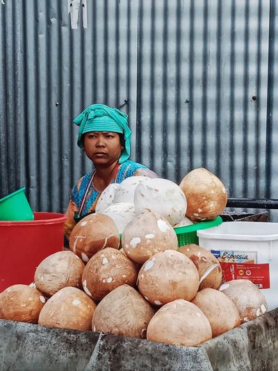 Portrait of young woman sitting on table. she is coconut trader