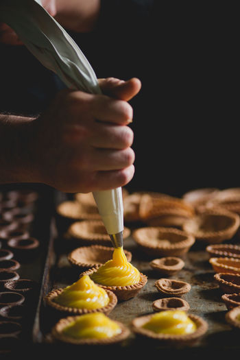 Close-up of baker piping mixture into pastries