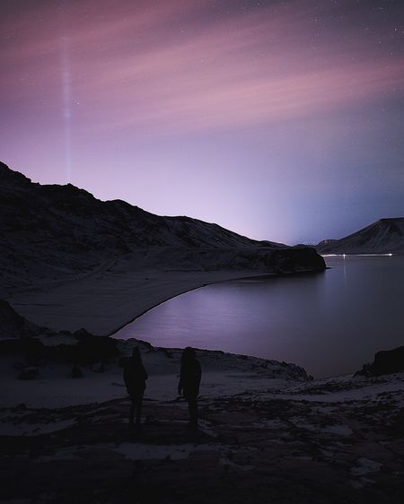Silhouette people on mountain against sky at night