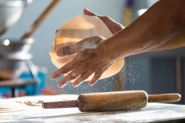 Cropped hands of person making chapatti in kitchen at home