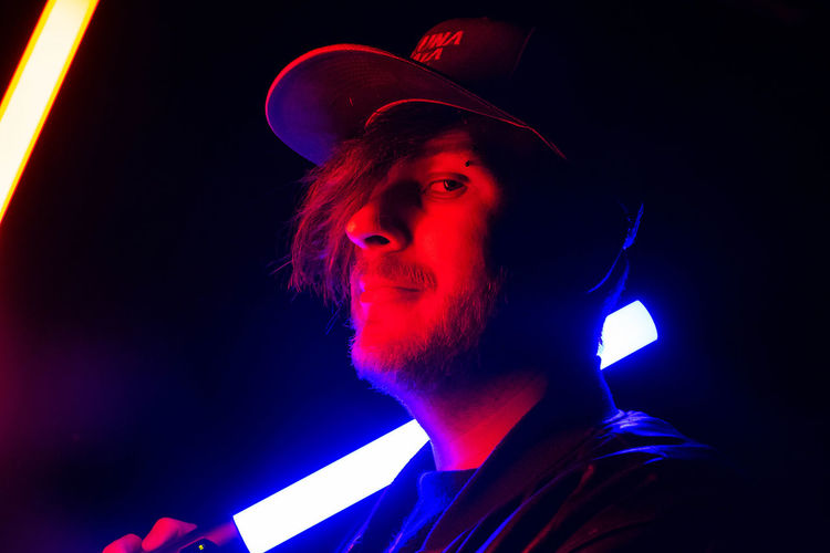 Portrait of young man holding lighting stick in dark