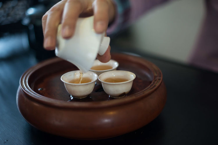 Cropped image of hand pouring chinese tea in cup