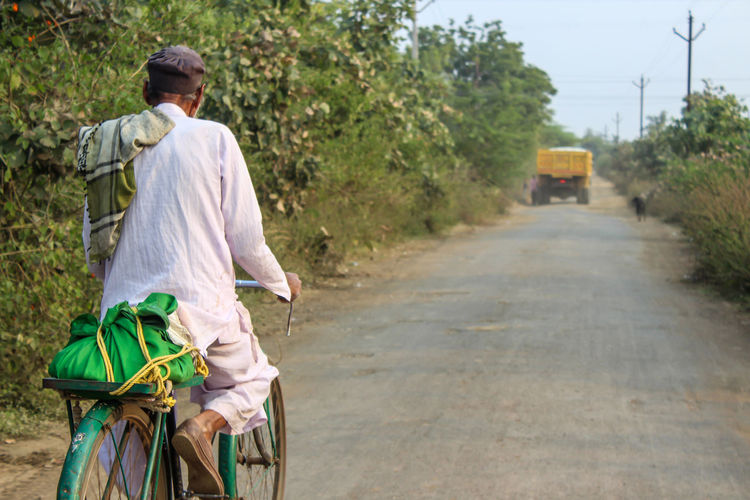 Rear view of man with bicycle on road