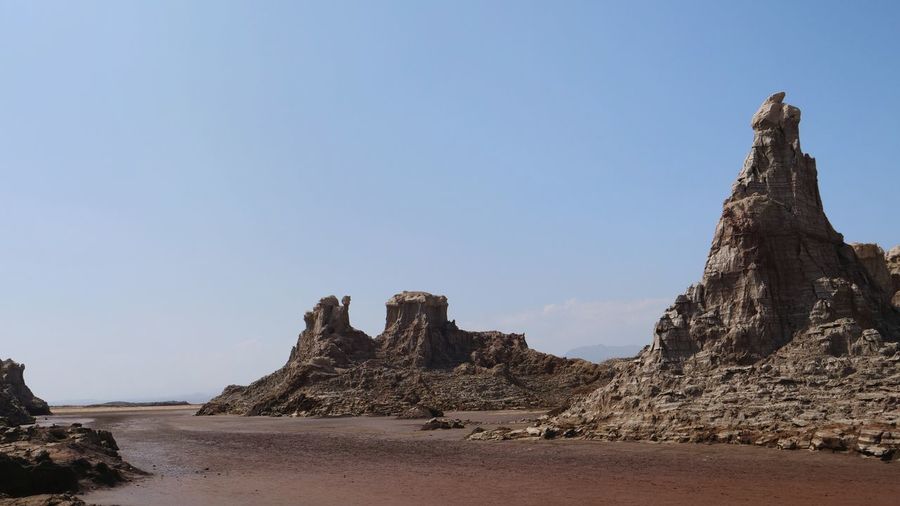 Rock formations on beach against clear sky